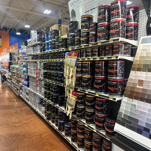 Shelves filled with paint cans on the left, with a paint swatch wall visible on the right at Peter's True Value Hardware.